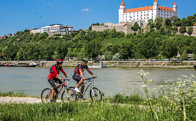 Cycling along the Danube past Bratislava Castle in Slovak Republic. ©Slovak Tourist Board