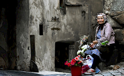 Old woman selling flowers in Sighisoara, Romania. Photo via Flickr:andrea floris