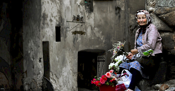 Old woman selling flowers in Sighisoara, Romania. Photo via Flickr:andrea floris 46.211675, 24.792709