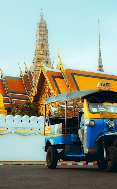 Tuk tuk parked outside a temple in Bangkok, Thailand bike tour. Unsplash@Mos Sukjaroenkraisri Shop