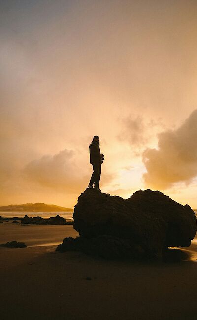 Standing on a rock at sunset in San Vicente de la Barquera, Spain. Unsplash:Paulina Herpel