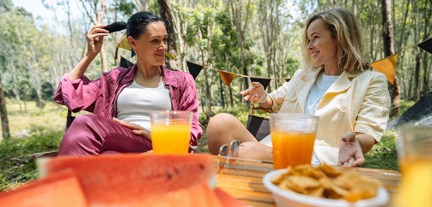 Two women enjoying food and drinks outside. Unsplash@George Dagerotip