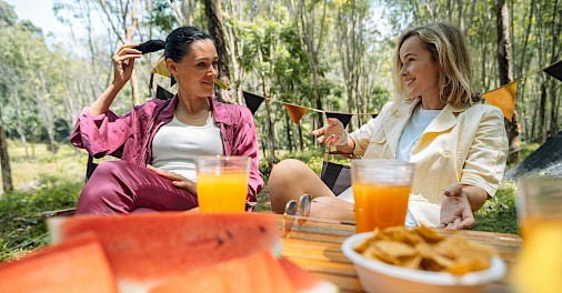 Two women enjoying food and drinks outside. Unsplash@George Dagerotip