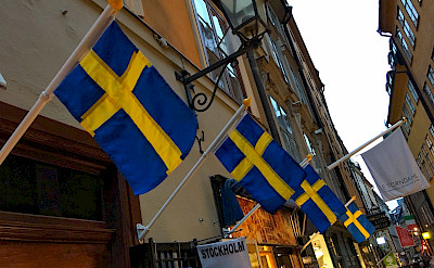 Flags flying on shopping street in Old Town Stockholm, Sweden. Flickr:Brian Dooley