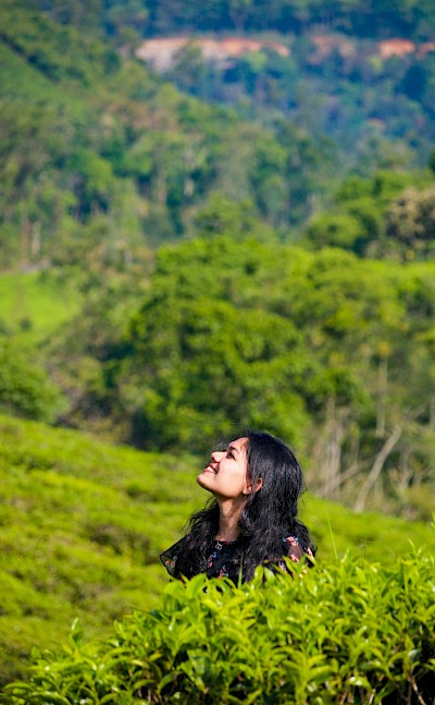 Smiling in the tea plantations, Vagamon, Kerala bike tour, India. Unsplash@Anas Anwar