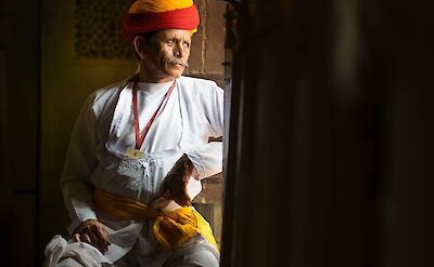 Local man looking out of the window of a palace, Udaipur. Unsplash@Aditya Siva