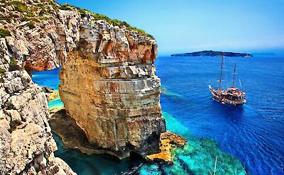 Tourist boat passing next to Trypitos (also known as "Kamara"), a natural rocky arch at Paxos island, Ionian Sea, GREECE. In the background, Antipaxos island.