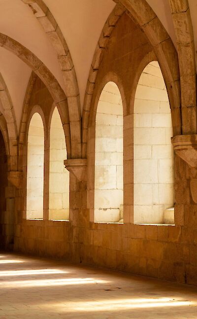 Sunlight through the arches of Alcobaça Monastery, Portugal. Unsplash@Luis Feliciano
