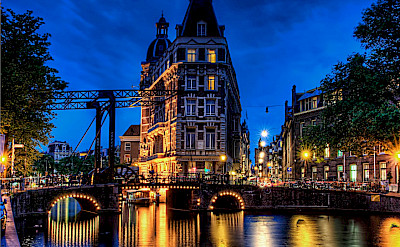 Amsterdam aglow in North Holland, the Netherlands. Photo via Flickr:Elyktra