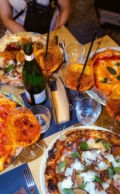 An al fresco dinner of wood-fired pizza and aperitifs in Sicily. pexels:ElsaBlom