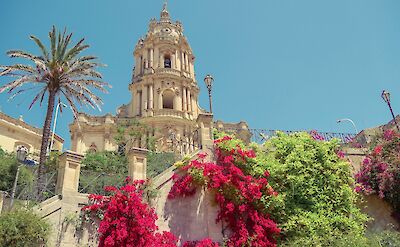 The Church of San Giorgio rising above the flowering streets of Modica, Sicily. unsplash:Andreas