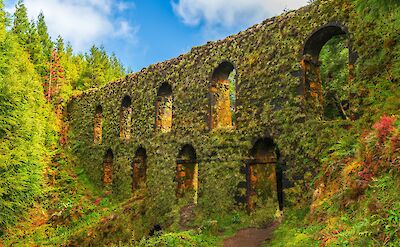 Discover the Muro das Nove Janelas, a mysterious moss-covered aqueduct nestled in the lush forests of Sao Miguel, a relic of Azorean history. Photo via AS Serenity-H
