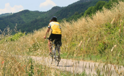 Cycling past fields and gentle hills in Italy. to-BTP
