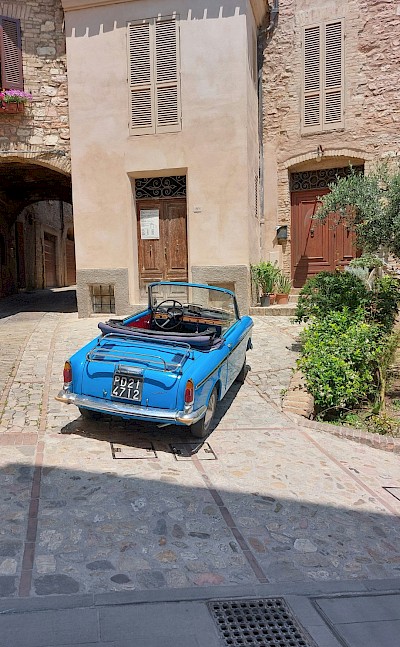 Blue car parked in Spello, Umbria walking tour, Italy. Unsplash@Csilla Monica Slezsak