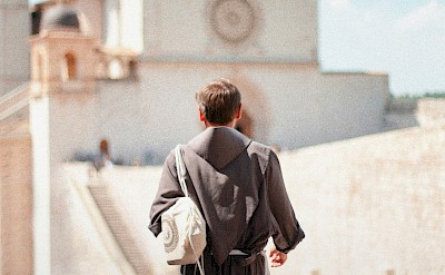 Priest walking to church in Assisi, Italy. Unsplash@Samuele Giglio