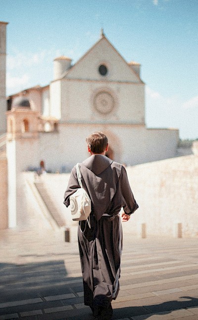 Priest walking to church in Assisi, Italy. Unsplash@Samuele Giglio